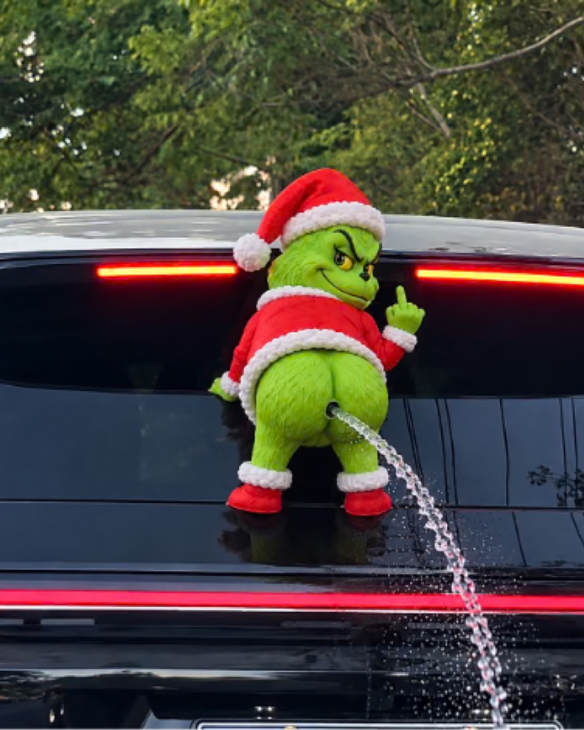 GrinchMist plush close-up spraying on a rear window